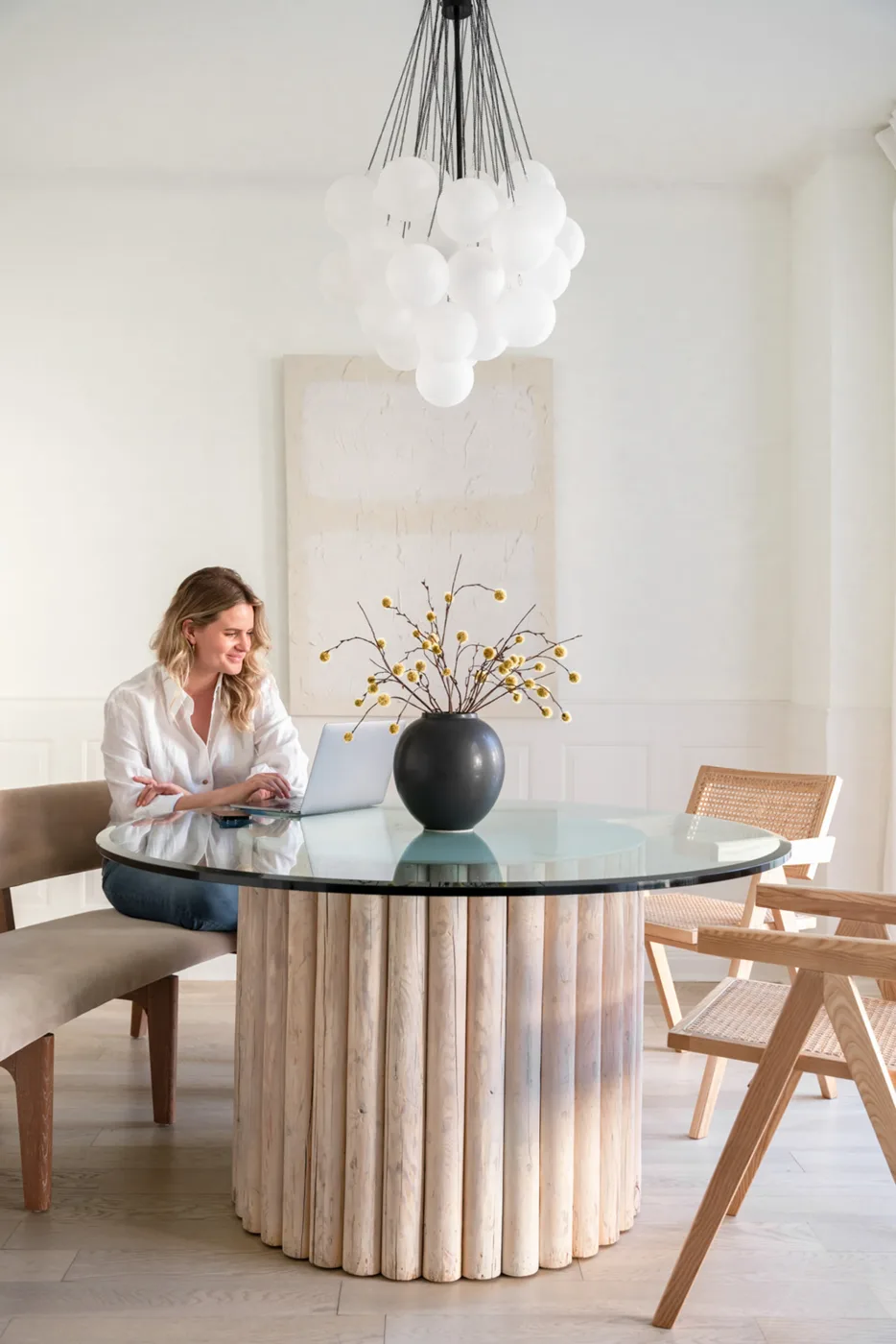 A woman working quietly at a round table in a calm, light-filled room