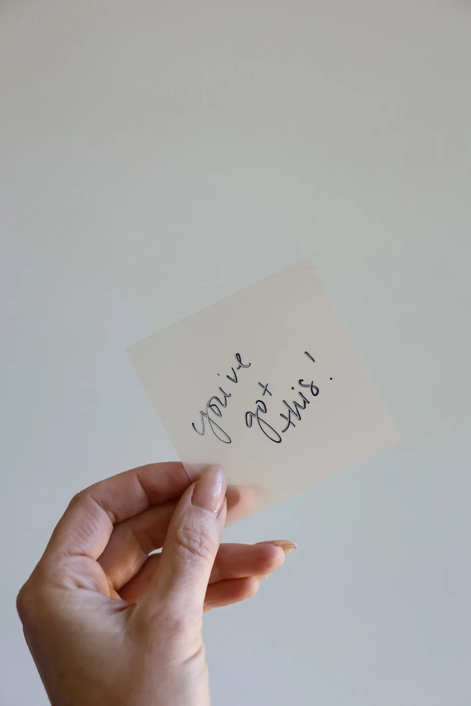 A hand holding a handwritten note that reads: you've got this!