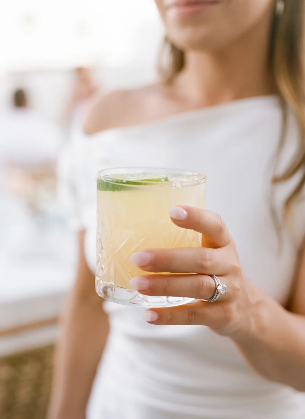 A woman in white holding a fresh drink, unwinding